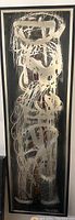 Full view of the framed abstract painting showing white swirling brush strokes on a black background with hints of color underneath.