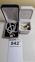 Full set of a pearl necklace and multiple pairs of earrings arranged in open jewelry boxes, showing the lot contents