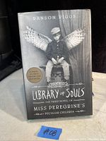 Cover of 'Library of Souls' showing a boy with wings sitting on a chair and title text.