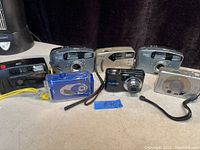 Overview of all 7 vintage cameras showing different brands and styles, arranged on a surface.