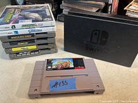 Image showing stacked Nintendo games including Nintendo 3DS cases and NES/SNES cartridges with a Nintendo Switch dock in background.