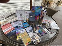 Overview of all items arranged on table including sketchbooks, watercolor paint set, colored pencils, brushes, and paint tubes.