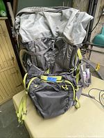 Front view of gray and black Trail Motion EOS-70L backpack with neon yellow accents, showing main compartment and front zippered pockets.