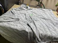 Gray knit poncho displayed spread out to show size and texture.