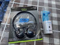 Photo of two headphones in original packaging on table: Circuit over-ear headphones and Sony blue earbuds in plastic case.