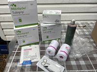 Photo showing several boxes of Mölnlycke Tubigrip elasticated tubular support bandages, packets of Inadine, two rolls of Medipore-H tape, a bottle of Betadine antiseptic, and a small medical tool kit with scissors and tweezers.