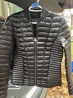 Front view of black Guess puffer jacket showing zipper and quilting detail.
