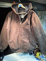 Brown heavy-duty canvas jacket on a hanger with front zipper and hood, showing overall condition and details.