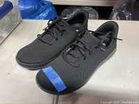 Pair of men's black casual lace-up shoes on table showing uppers and laces.