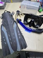 Top view of the snorkeling set on a tan surface showing one flipper, snorkel, and diving mask.