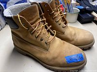 Pair of tan Timberland boots on a table showing sides, laces, padded collar, and overall condition