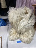 Front and side view of the winter boots showing creamy white faux fur material and thick design.