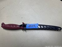 Photo of the fillet knife sheathed with a blue numbered tape attached to sheath