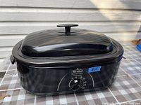 Front view of Rival roasting oven with lid on showing control knob and temperature markings.