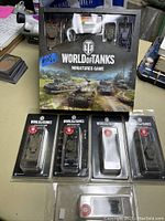Front view of the World of Tanks Miniatures Game starter box with four extra tanks in blister packs positioned below the box.