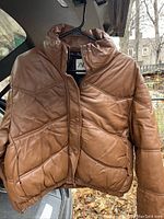 Front view of the brown ZARA puffer jacket showing snap button closure, pockets, and quilted pattern.