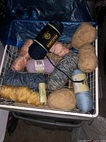 Close-up top down view of yarn skeins of various colors, types and brands (Homespun, Soft). Colors include navy blue, beige, pale peach, soft blue, lilac, cream, and multicolored varieties.