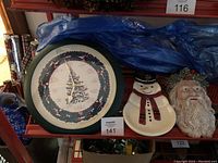 Shelf view showing the wall clock, snowman dish, and Santa head wall hanging together.