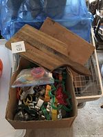 Wide shot showing the large box filled with assorted cookie cutters of different sizes and colors alongside two wooden cutting boards resting above the box.