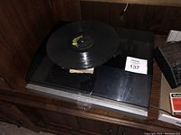Turntable with record sitting on top with closed transparent lid, placed on wooden furniture
