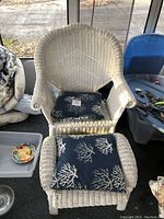 White wicker chair with curved back and blue coral patterned seat cushion
