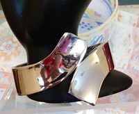 Silver-toned reflective cuff bracelet displayed on black jewelry stand