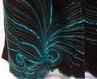 Close-up detail showing the blue sequin feather-like pattern on the dark brown linen skirt