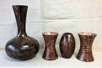 Front view of four wooden vases arranged in a line showcasing shapes and wood grain