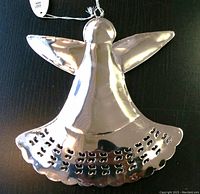 Close-up of large silver angel ornament with shiny metallic finish and perforated design on dress