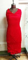Red sleeveless silk dress displayed on mannequin, showing fitted design and textured fabric.