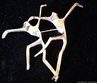 Silver-tone dancers brooch shaped as two abstract human figures dancing, on black background