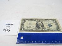 1935 B Silver Certificate $1 bill laid flat next to blue ruler for size reference