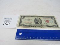 Top side of 1953 A series $2 bill with red seal, showing serial number and Thomas Jefferson portrait on front.