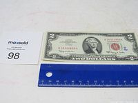 Photo showing the front of the 1963 A $2 bill next to a ruler for size reference on a white background.