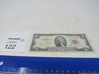 Side view photo of the 1963 A red seal two dollar bill showing its full length along a ruler for size reference.