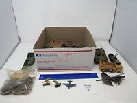 Overview photo of the lot showing military figures, plane, and box with tanks and trucks inside.