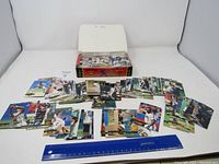 Wide shot displaying a partially open box filled with baseball cards and several cards spread in front of it on a white surface.