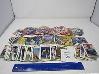 Overview of the large pile of mixed baseball cards spread on a white surface with a measuring ruler indicating size range.