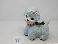 Front-left view of ceramic puppy planter showing textured curly fur, black eyes, pink cheeks, and hollow planter section on its back.