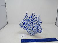 Blue glass abstract bowl shown from one angle with a ruler for size reference.