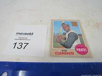 Bob Roberto Clemente baseball card shown with protective sleeve and placement next to MaxSold tag 137.