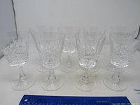 Front view showing the set of eight crystal wine glasses with stems and detailed cut patterns.
