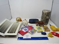 Lot arranged on white background showing all items including elephant figurine, heavy log, hand tools, vent covers, decorative items, and small packets.
