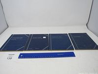 Four blue coin collection books arranged side by side on white background, showing front covers.