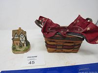 View of Longaberger basket filled with red and blue star-patterned fabric liner and miniature cottage figurine beside it.