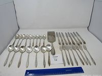 Full view of the utensils laid out showing spoons, forks, and spatula with a ruler for scale.