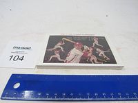 Front view of the sealed Philadelphia Phillies Tasty Cake baseball card showing a player swinging a bat, with a ruler and lot tag for scale.