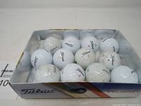 Top and front view of dozen used Titleist Velocity golf balls, showing some with dirt and wear marks.
