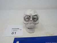 Front view showing the white skull with large clear lens lights for eyes, some surface texture details visible.