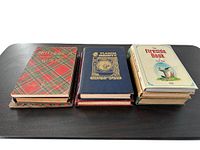 Nine antique poetry books arranged in three stacks on a dark surface showing covers and spines.